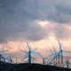 Sunset illuminates storm clouds behind giant windmills.